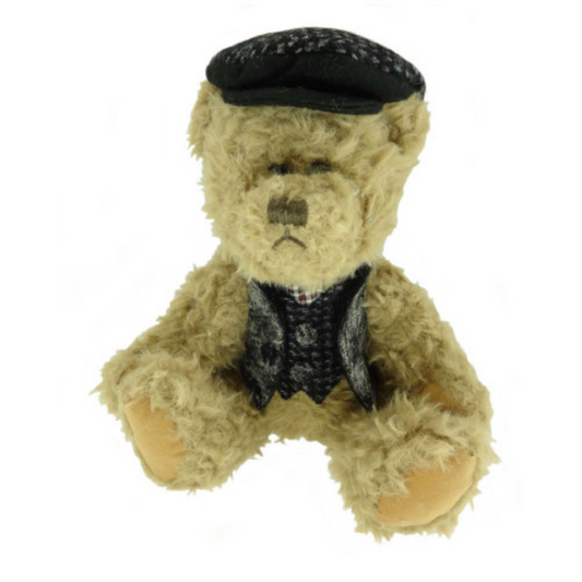 Teddy bear wearing a black harris cap and vest on a white background